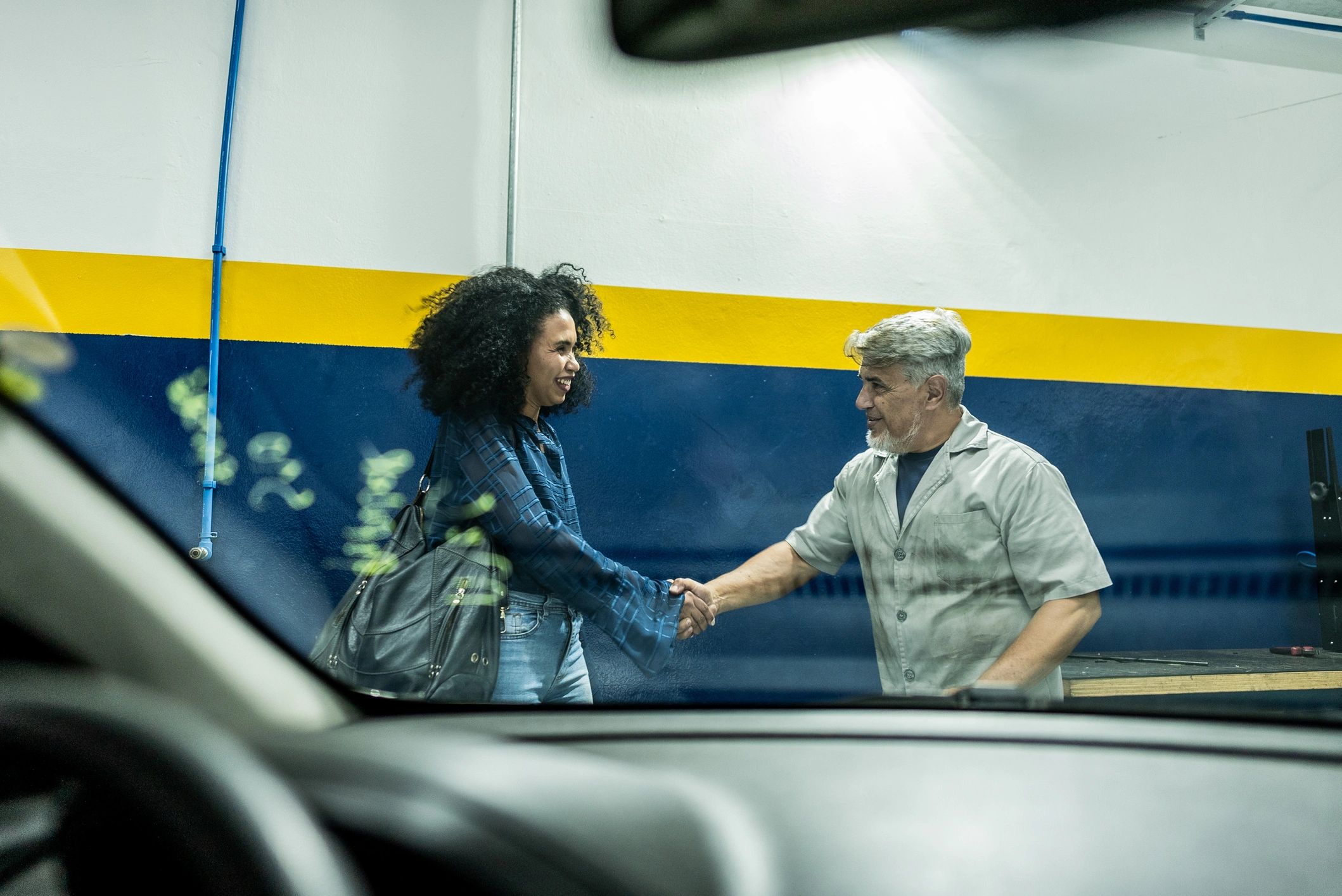 Auto mechanic greeting a customer at a repair shop