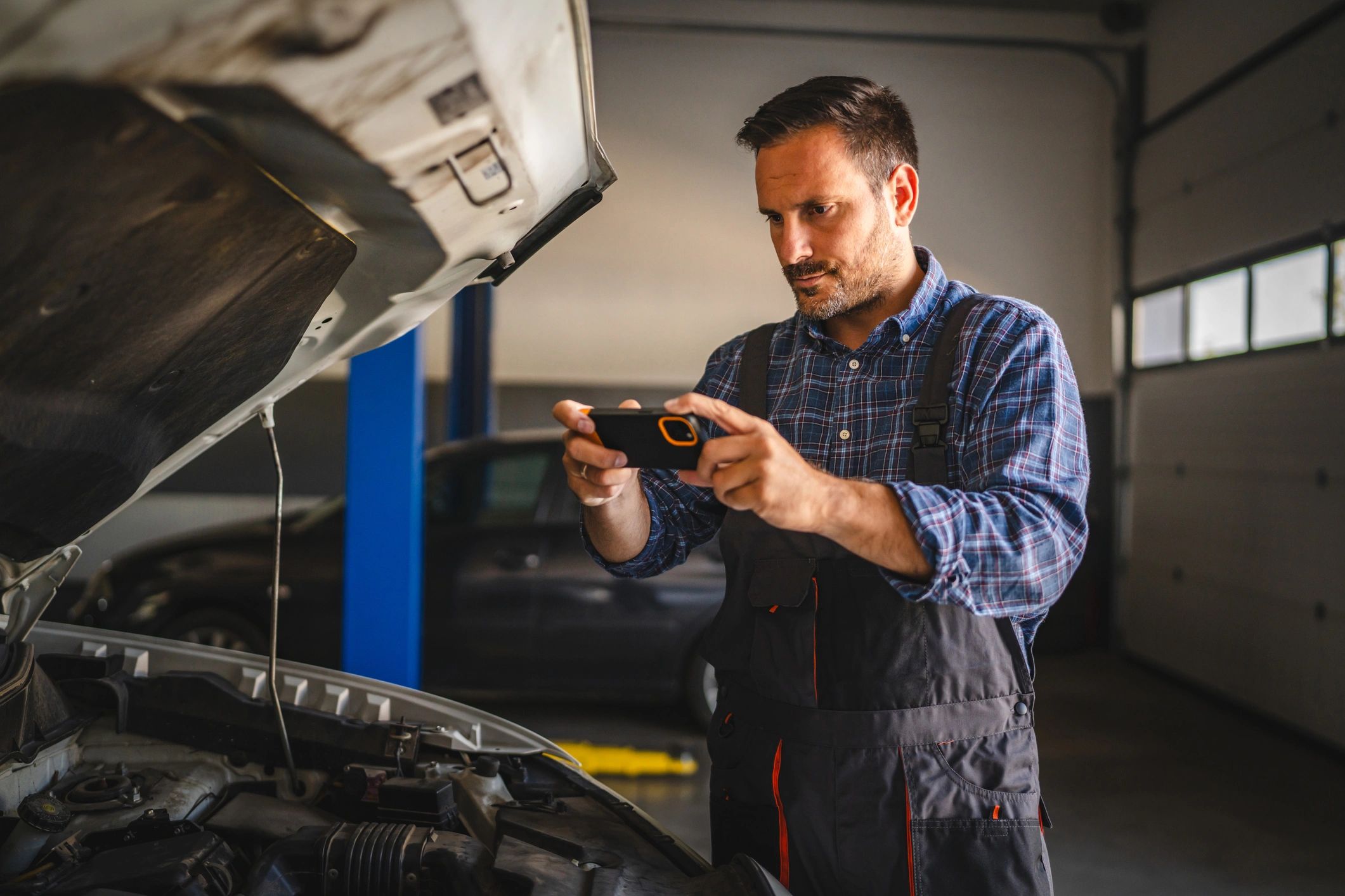 Mechanic photographing a car engine for modern diagnostics